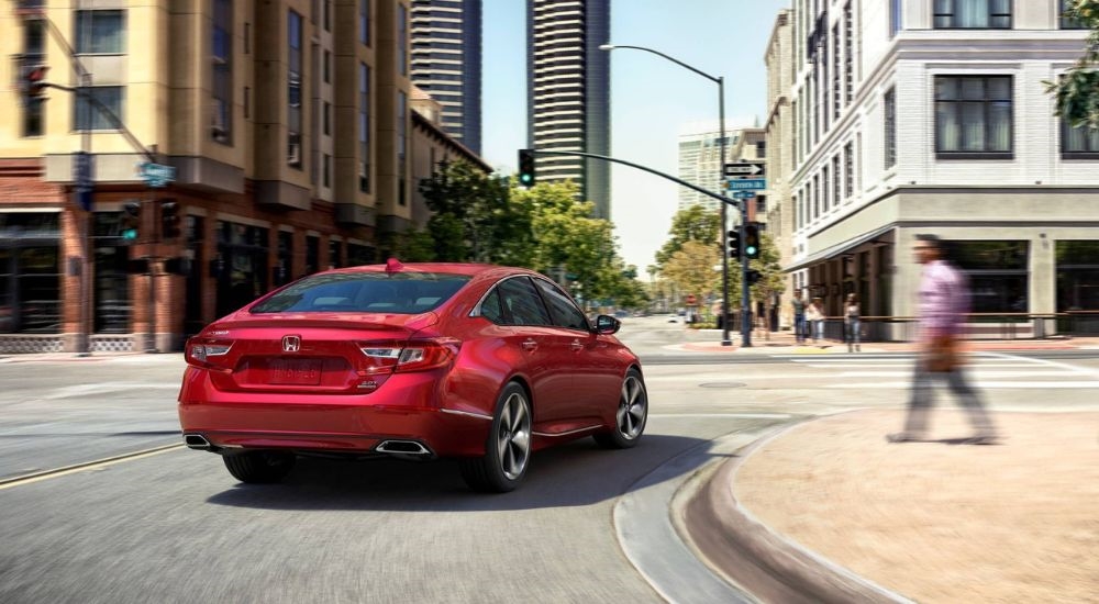 A red 2020 Honda Accord Touring is shown driving on a city street after leaving a used car dealership near North Bergen.