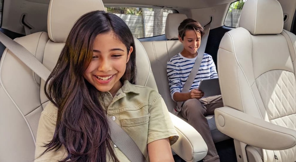 Smiling children sitting in the back seats of a 2022 Honda Pilot.