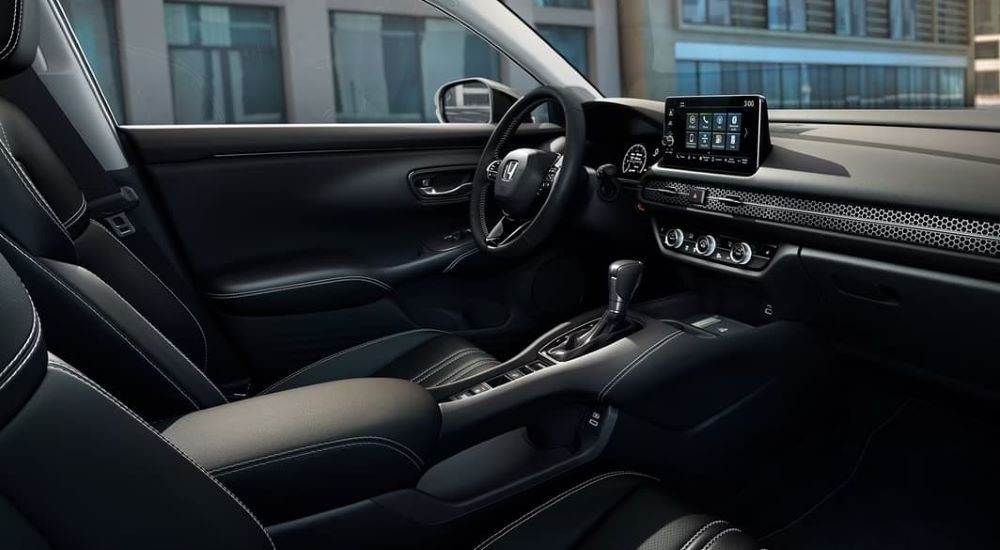 The black interior, front seats, and infotainment screen of a 2023 Honda HR-V.