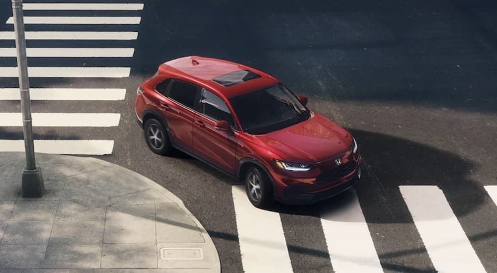 A red 2023 Honda HR-V turning a corner on a city street.