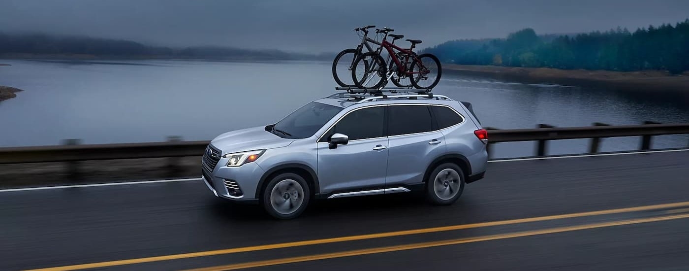 A blue 2024 Subaru Forester is shown driving on a highway.