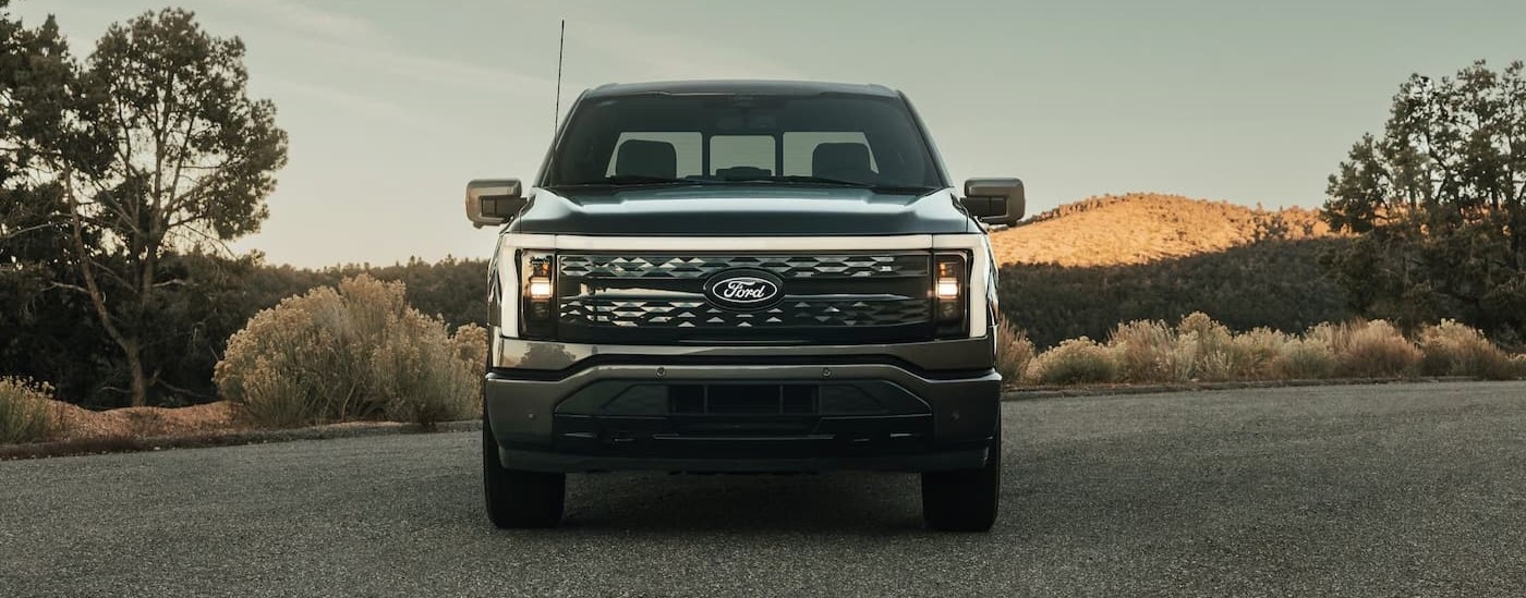 A black 2022 Ford F-150 Lightning for sale is shown parked near a hill.