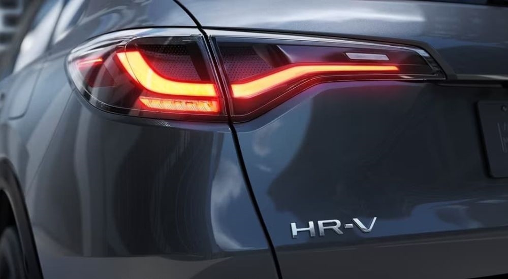 A close up shows an illumintaed taillight on a grey 2024 Honda HR-V for sale.