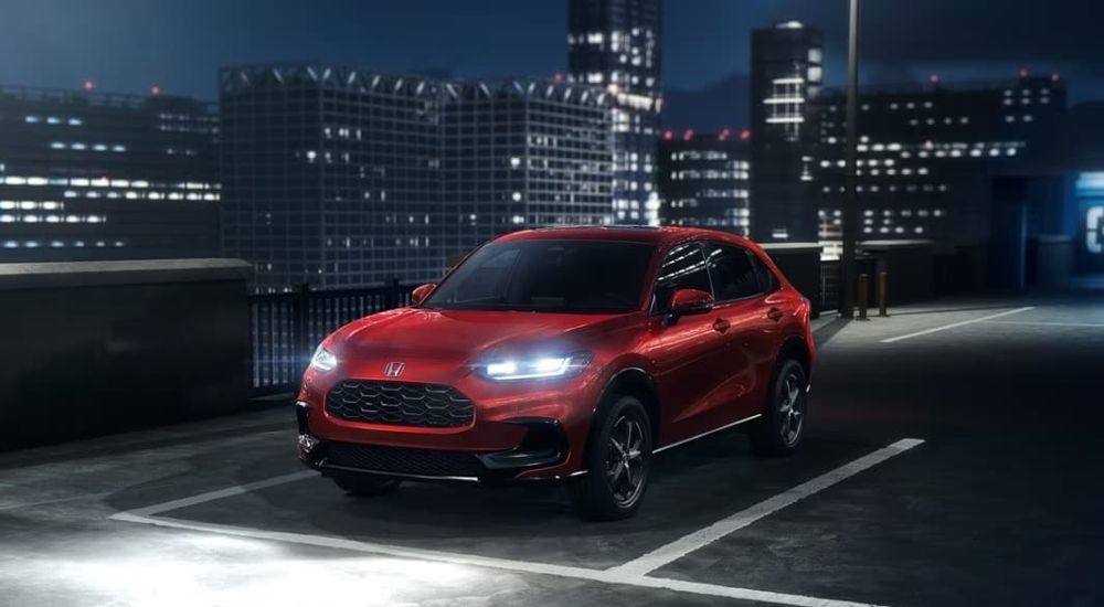 A red 2024 Honda HR-V EX-L is shown parked on a city rooftop at night.