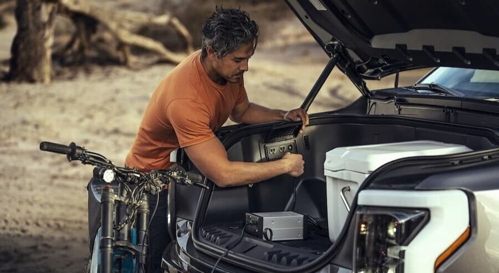 A person is shown utilizing the electric outlet on a 2024 Ford F-150 Lightning.