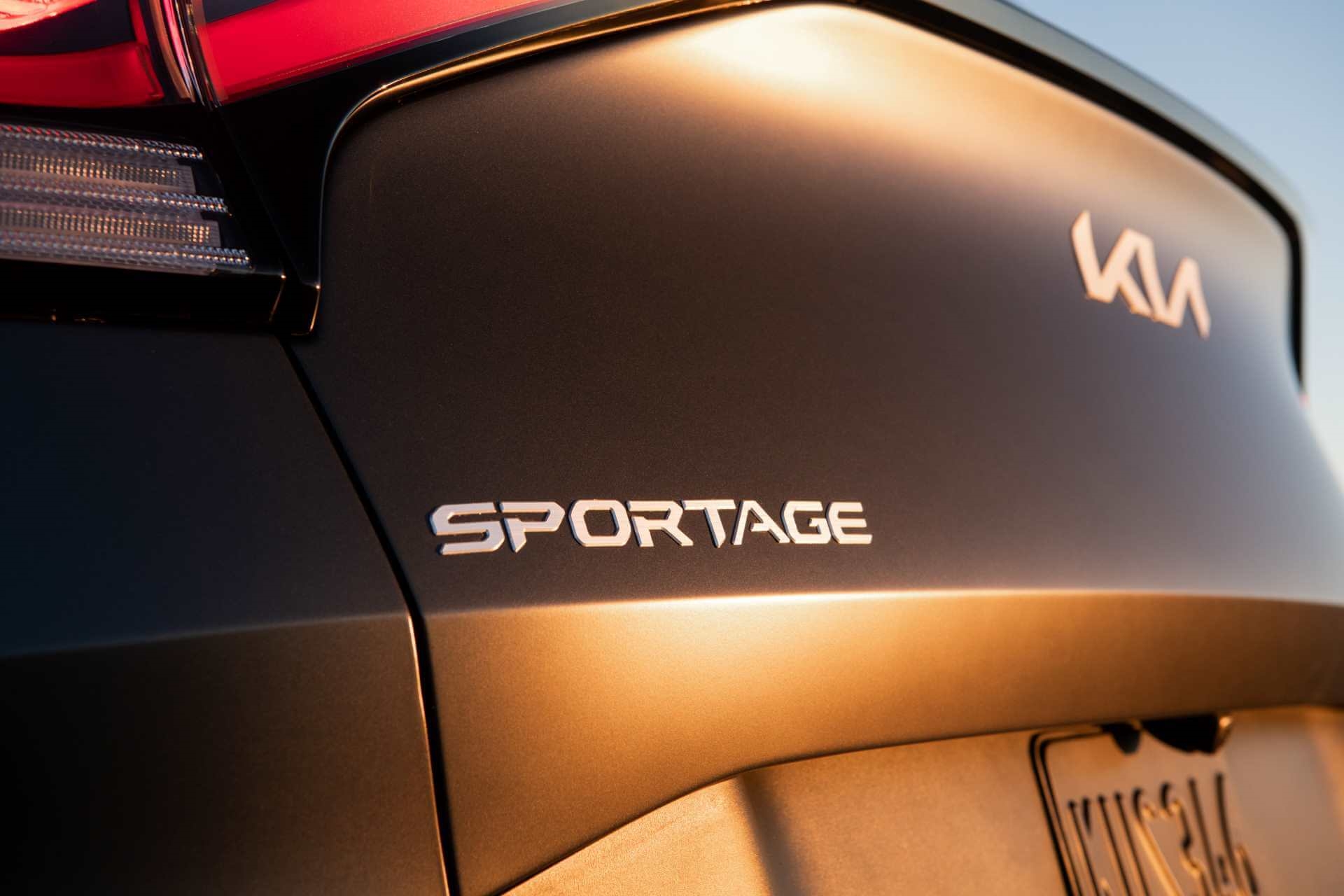 Golden hour close-up of name badge on rear tailgate of a black Kia Sportage model