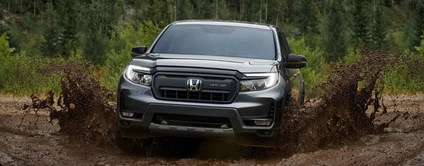 A grey 2024 Honda Ridgeline HPD+ is shown kicking up mud after leaving a Honda dealer in Middletown.