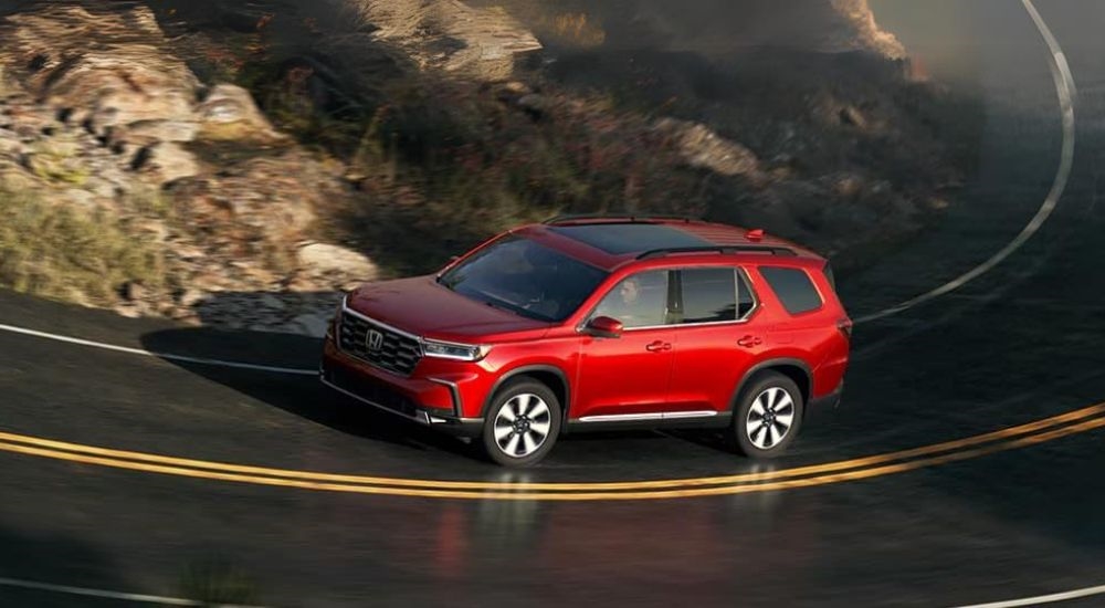 A red 2025 Honda Pilot is shown rounding a corner.