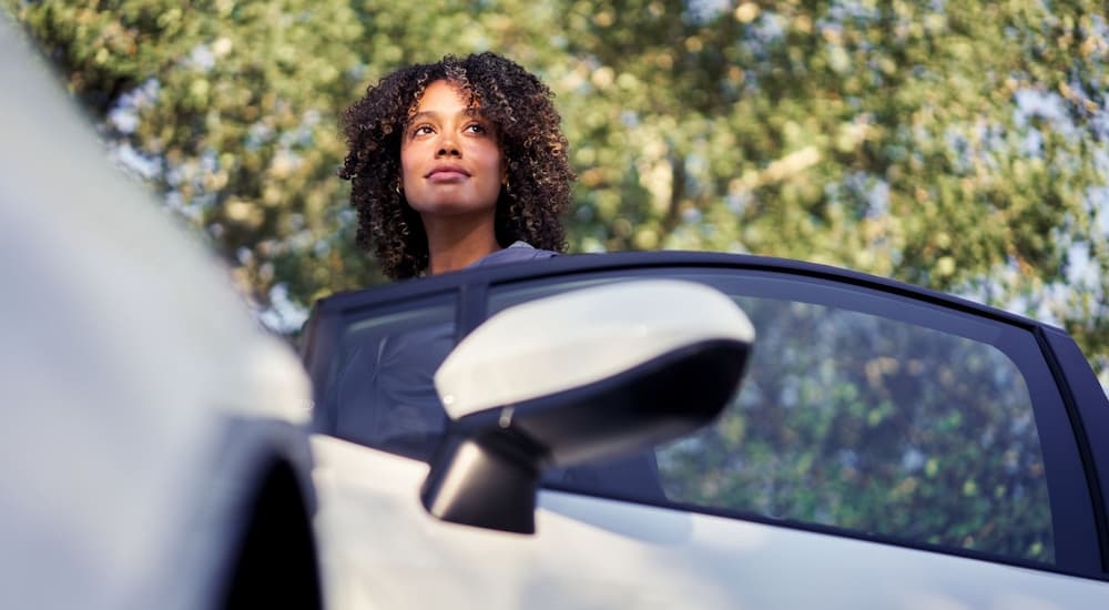 A woman standing next to the open door of a white 2024 Toyota Corolla.
