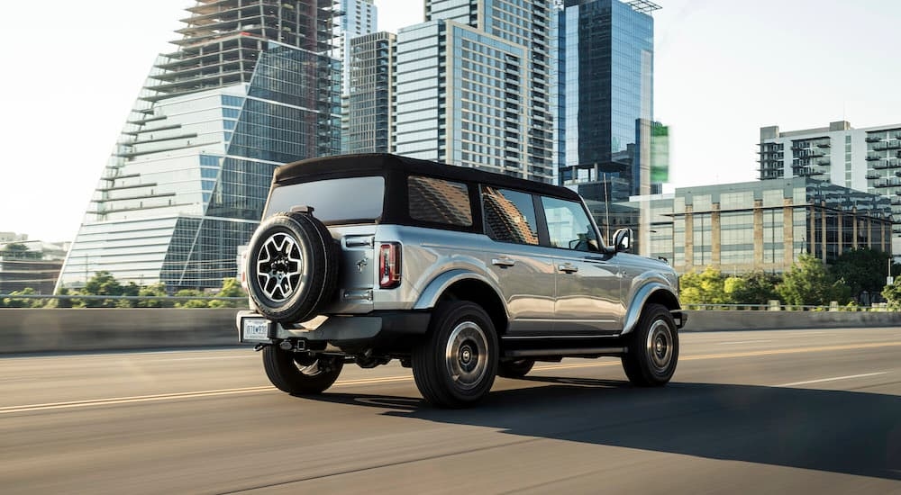 A silver 2021 Ford Bronco for sale is shown from the rear at an angle.