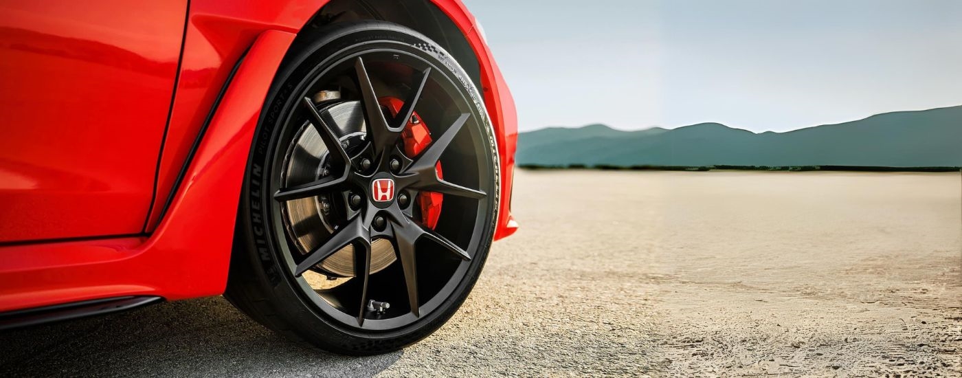 A close up shows the black wheel on a red 2024 Honda Civic Type R.
