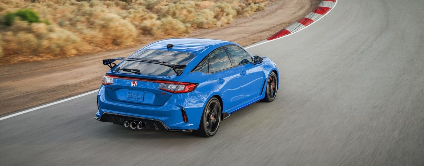 A blue 2024 Honda Civic Type R is shown rounding a corner on racetrack.