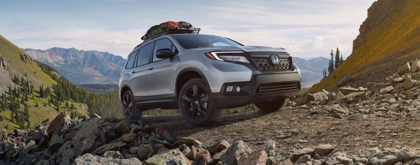 A silver 2020 Honda Passport is shown driving on a rocky trail.