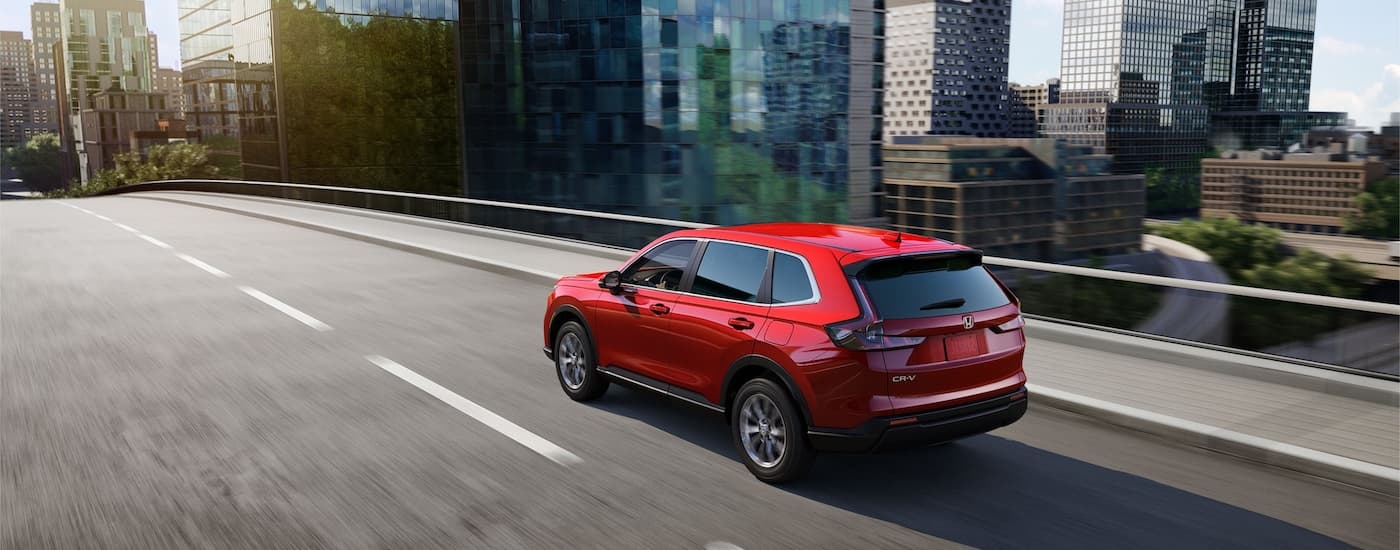 A red 2024 Honda CR-V is shown driving on a bridge to visit a Honda dealer near Maltby.