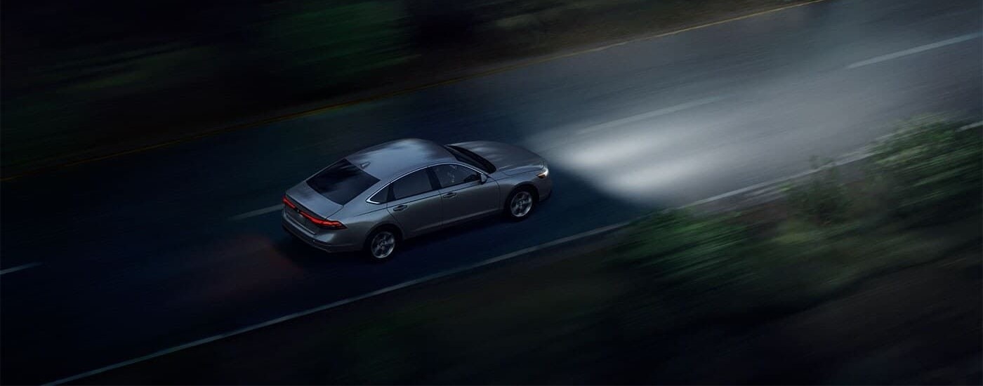 A silver 2024 Honda Accord LX is shown driving at night.