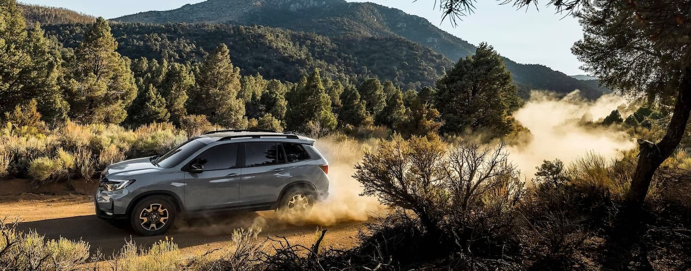 A grey 2023 Honda Passport Trailsport is shown driving on a duty trail.