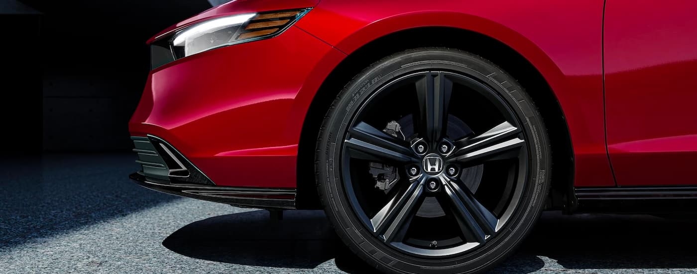 A close up view of the side of a red 2023 Honda Accord Sport Hybrid shows the wheel and headlight.