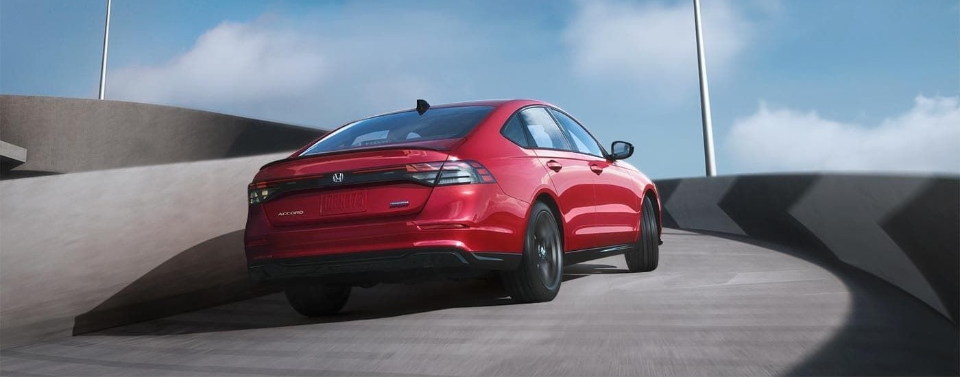 A red 2023 Honda Accord Sport-L Hybrid is shown driving up a ramp.