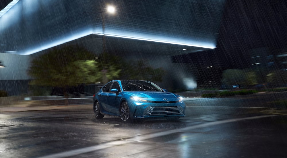 A blue 2025 Toyota Camry XSE driving at night in the rain.