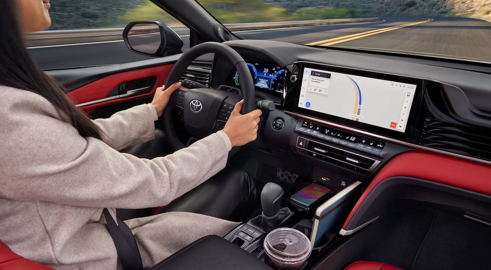 A woman driving a 2025 Toyota Camry XSE with red interior accents.