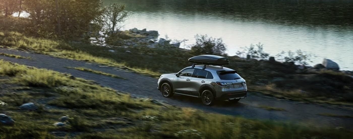 A grey 2023 Honda HR-V Sport is shown driving past a river.