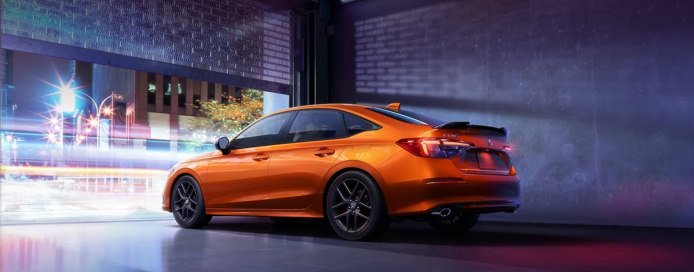 An orange 2022 Honda Civic Si is shown from the rear at an angle.