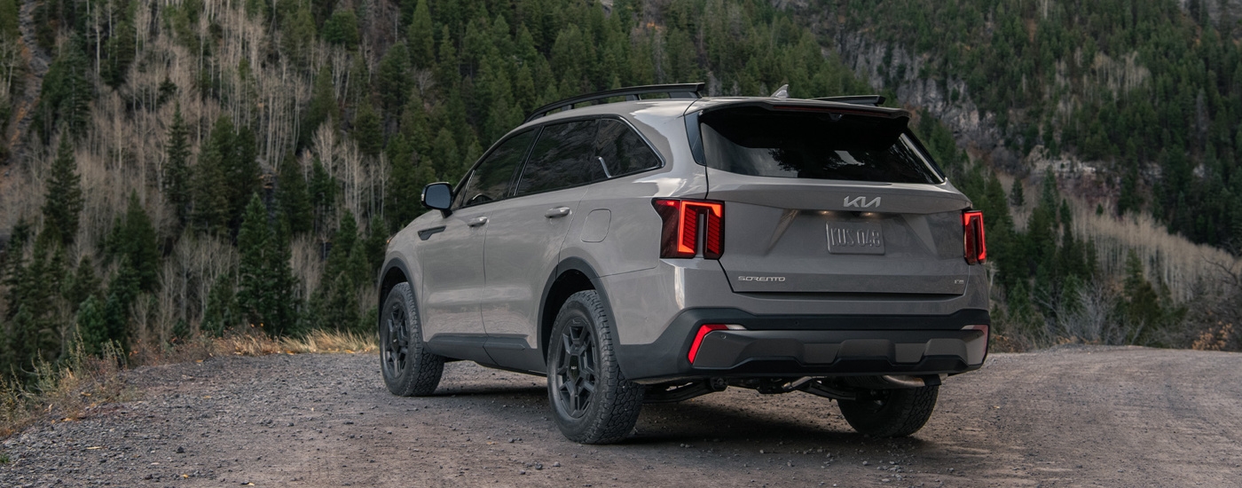 Rear view of a grey 2024 Kia Sorento X-Pro SX Prestige parked in the mountains.