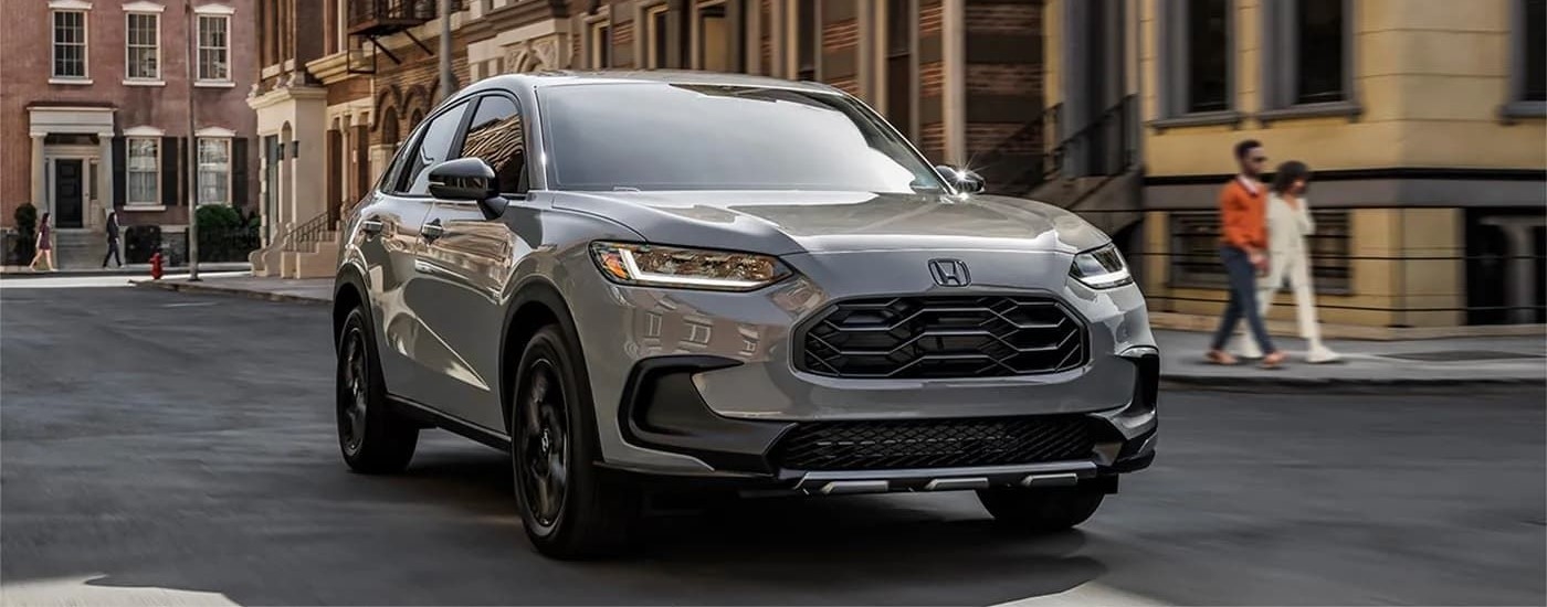 A grey 2023 Honda HR-V is shown driving on a city street after visiting a Honda dealer near Bothell, WA.