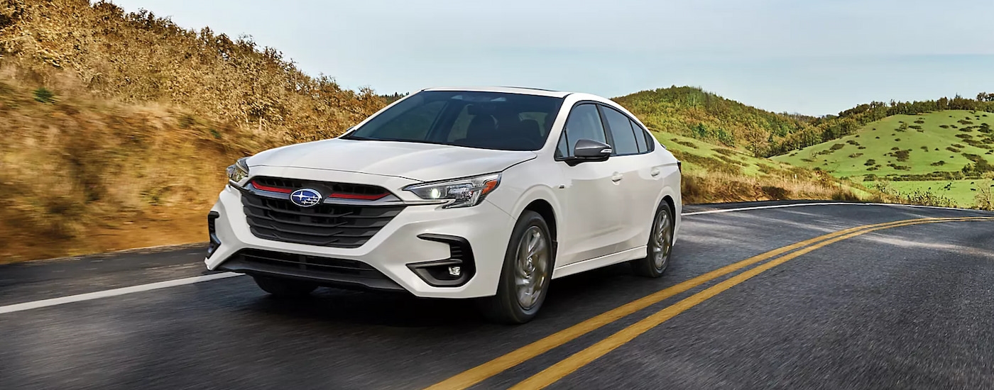 A white 2024 Subaru Legacy Sport driving on an open road.