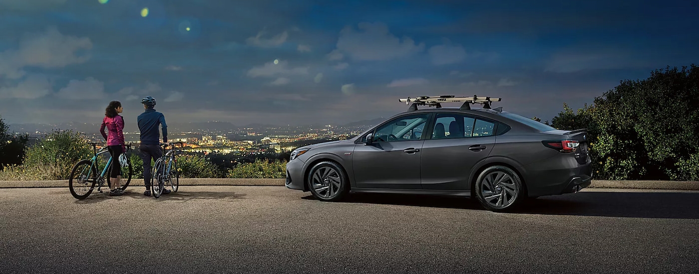 Side view of a grey 2024 Subaru Legacy Sport overlooking a city at night.