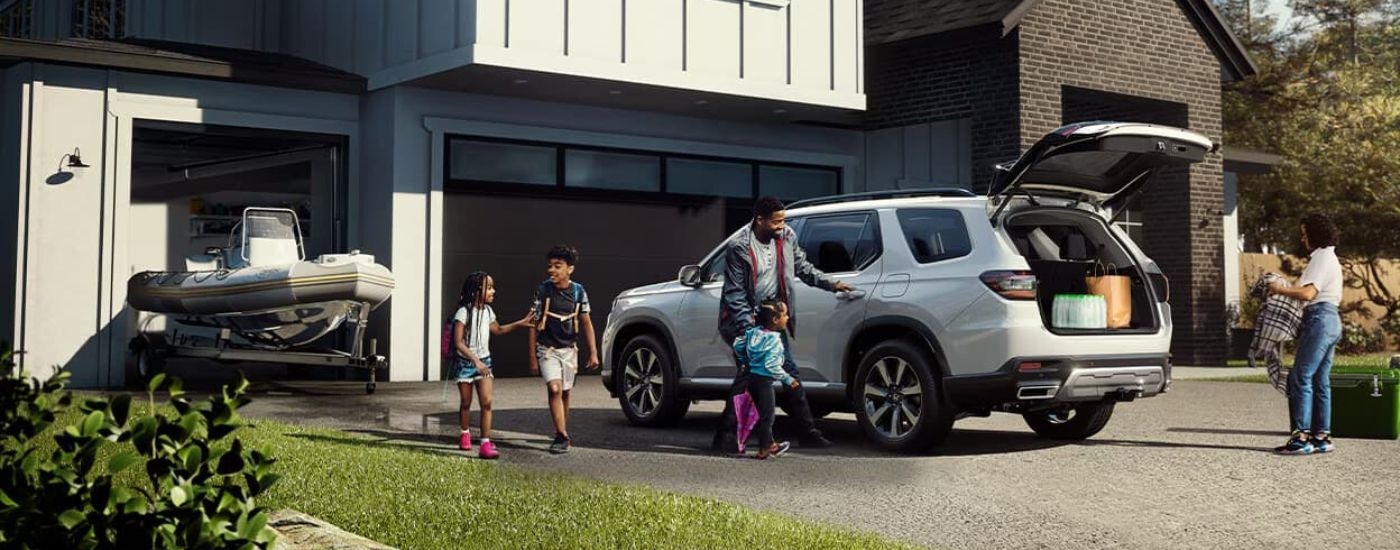 A white 2023 Honda Pilot Touring is shown parked on a driveway.