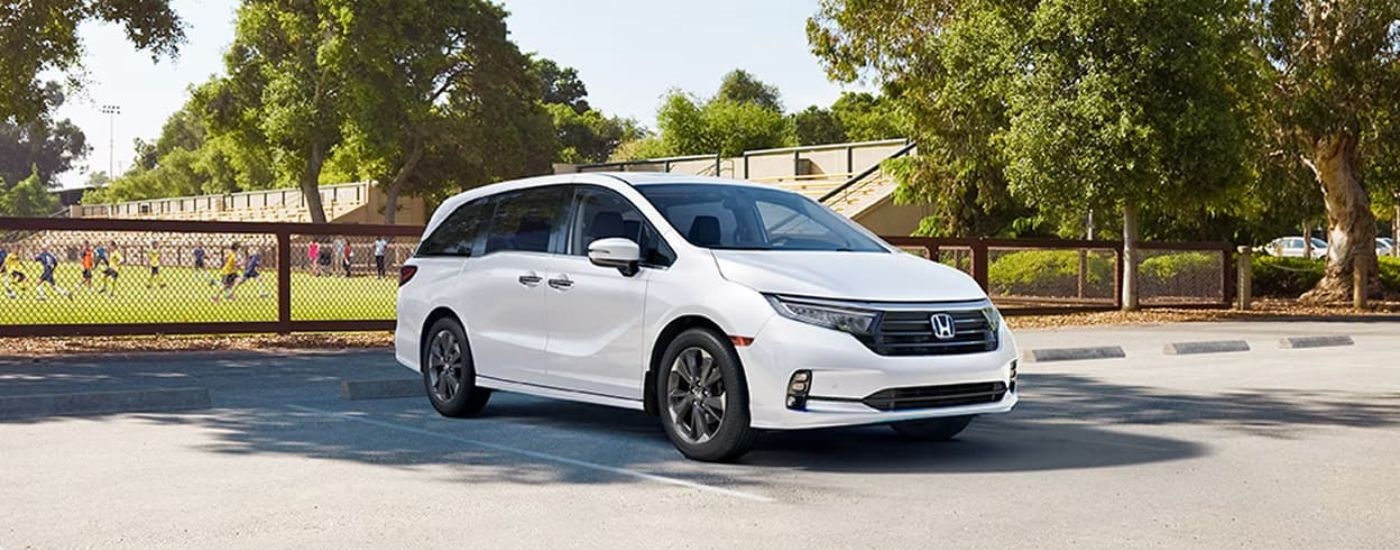 A white 2023 Honda Odyssey is shown parked near a soccewr field.