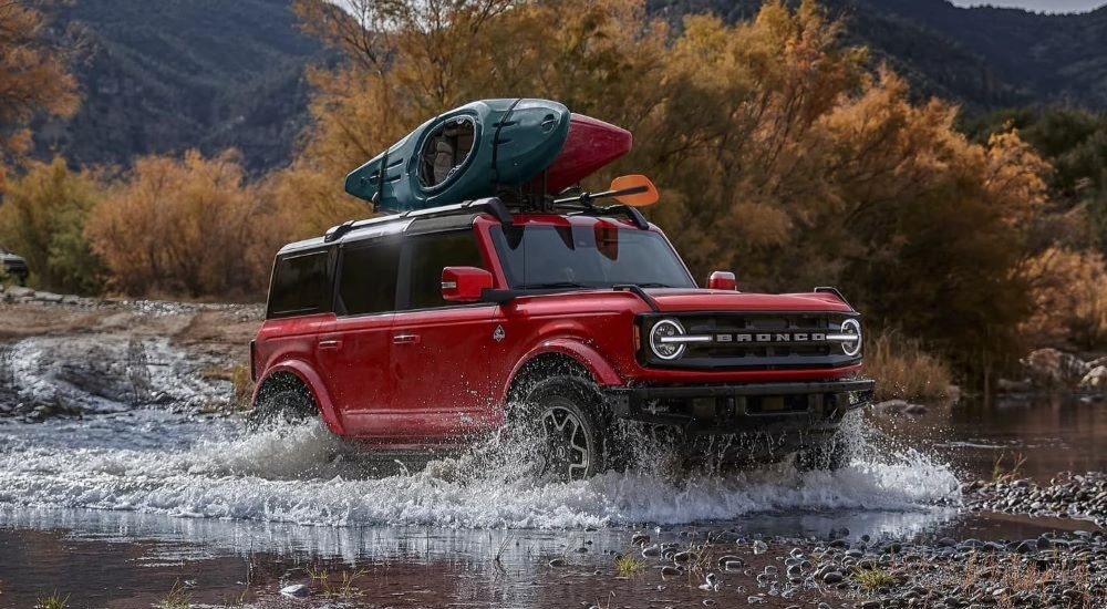 A red 2024 Ford Bronco Big Bend driving over a shallow lake.
