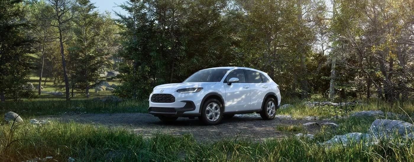 A white 2024 Honda HR-V is shown parked near a forest.