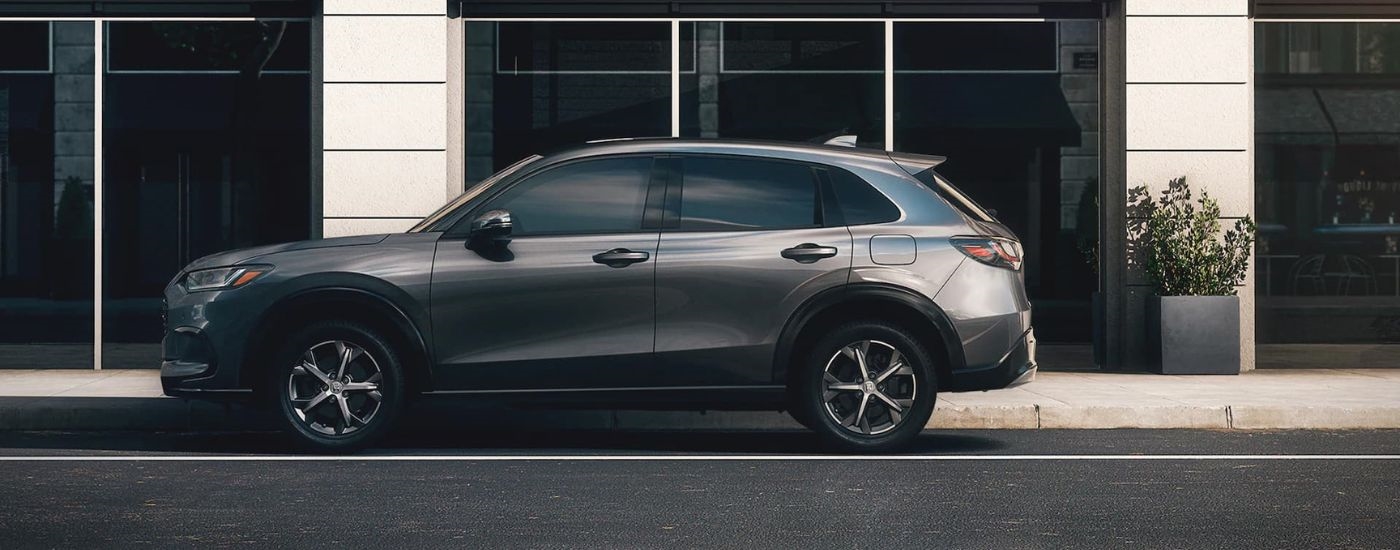 A grey 2023 Honda HR-V for sale is shown parked in front of a building.