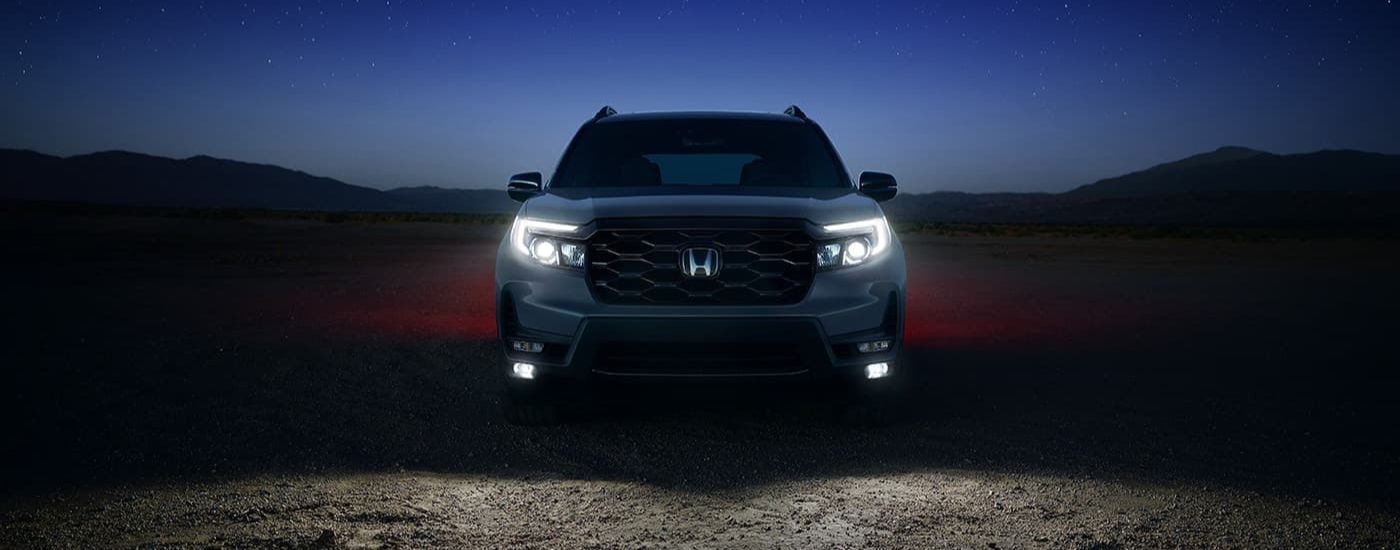 A silver 2024 Honda Passport Elite is shown at night.