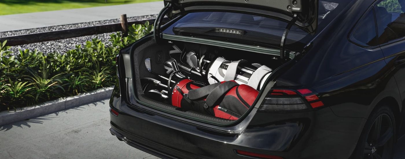Golf clubs are shown in the trunk of a black 2024 Honda Accord.