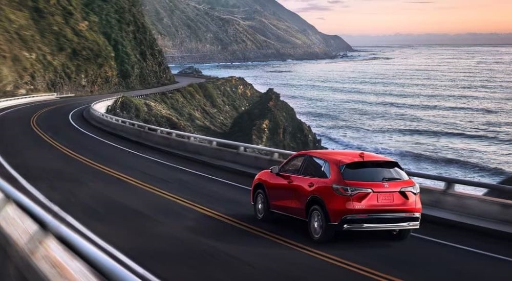 A red 2024 Honda HR-V EX-L is shown driving near the ocean after leaving a Kirkland Honda dealer.