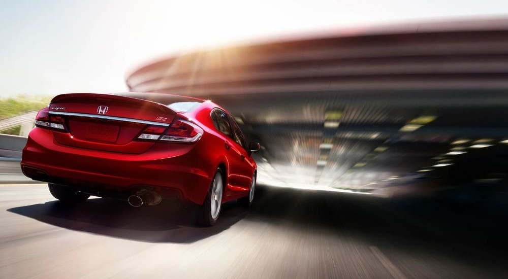 A red 2014 Honda Civic Si is shown driving on a sunny day.