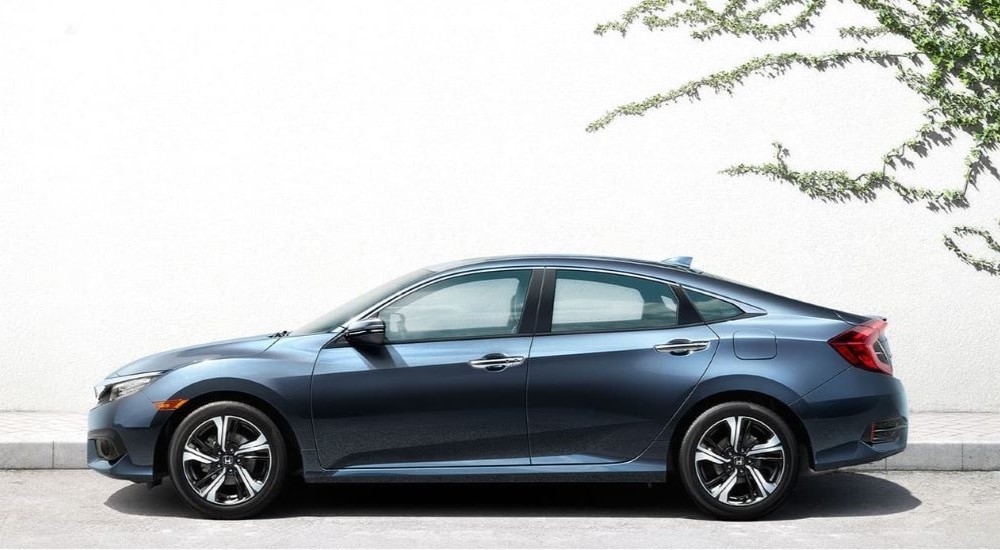 A blue 2016 Honda Civic is shown near a wall covered in ivy.