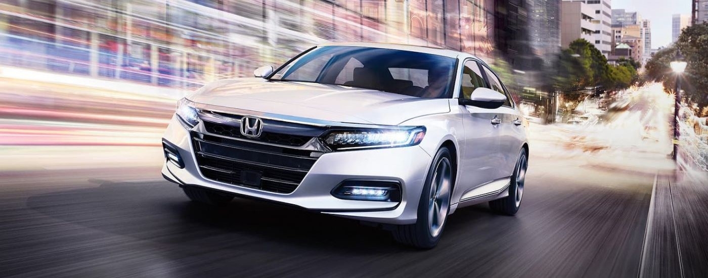 A white 2020 Honda Accord Touring is shown from the front at an angle. after leaving a used Honda dealer.