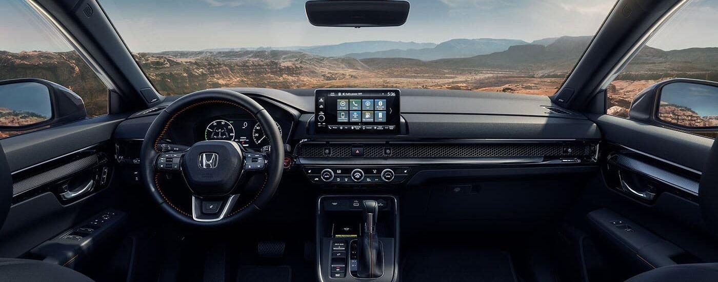 The black interior and dash of a 2023 Honda CR-V Sport Touring Hybrid is shown.