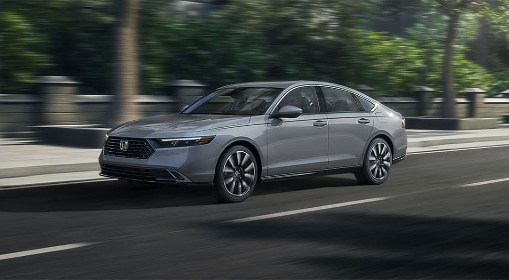 A grey 2024 Honda Accord Touring Hybrid driving in a city.