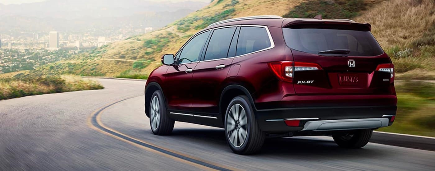 A red 2020 Honda Pilot Touring is shown driving on a highway.