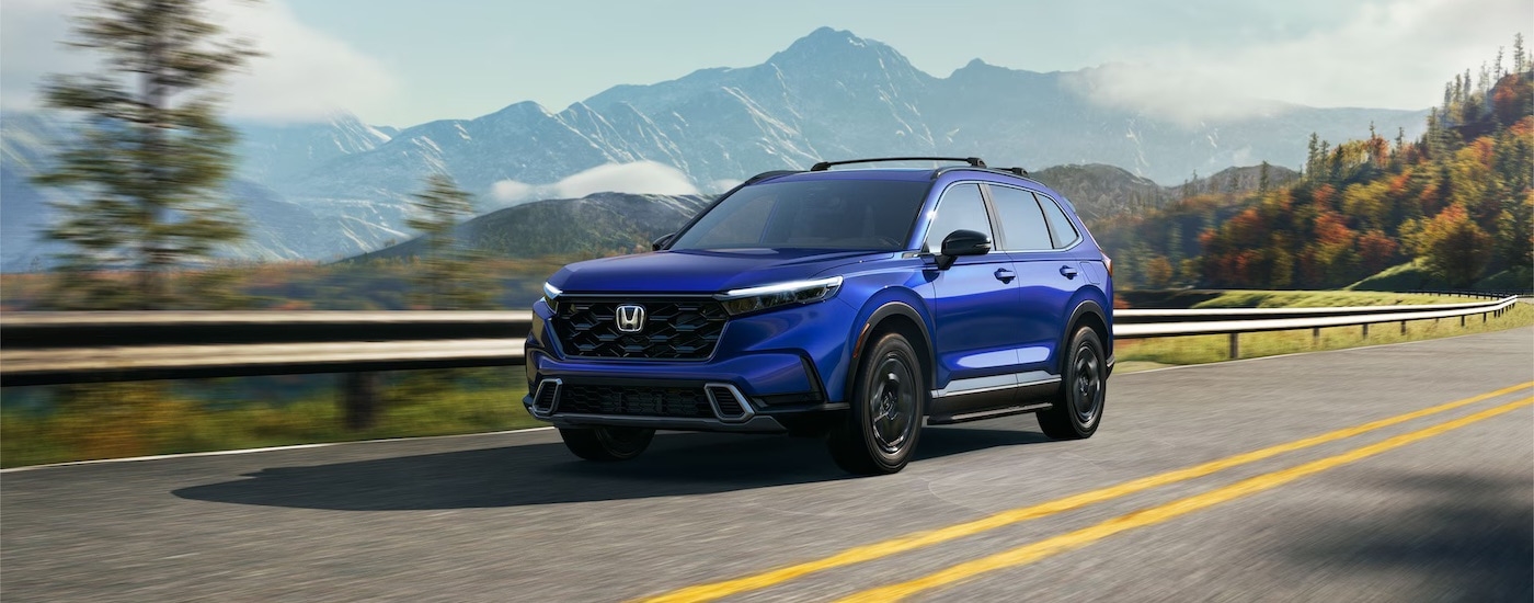 A blue 2022 Honda CR-V is shown from the front at an angle near a dealer that has used hybrid vehicles for sale.