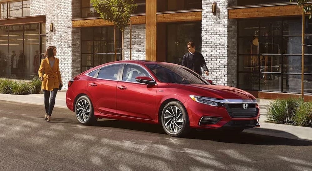 A red 2021 Honda Insight Touring Hybrid is shown parked near a curb.