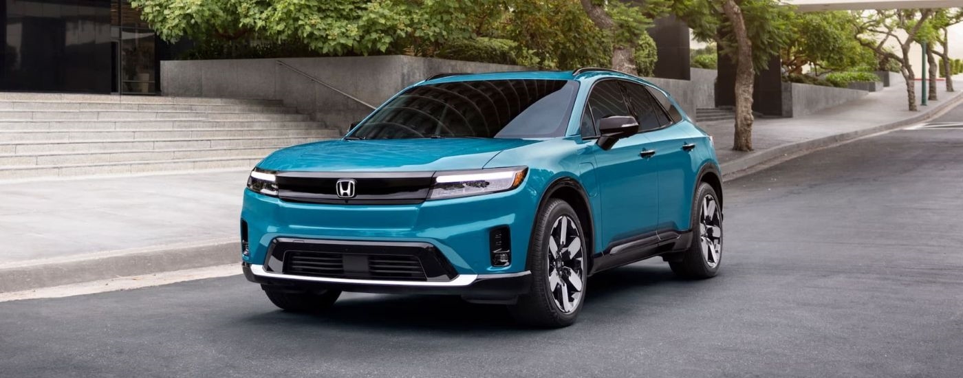 A green 2024 Honda Prologue for sale is shown driving on a city street.