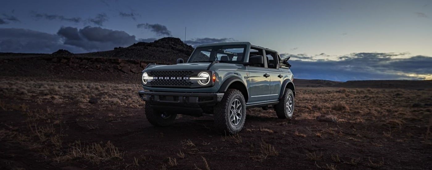 A grey 2024 Ford Bronco Badlands parked in a plain at sundown.