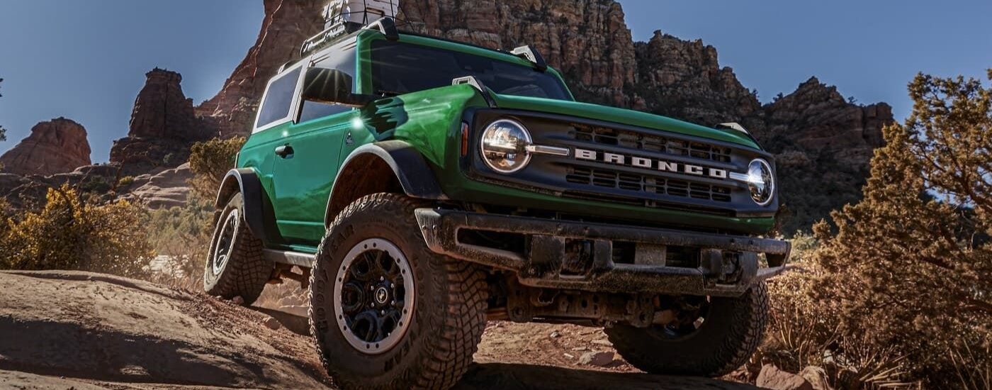 A green 2024 Ford Bronco driving down a hill.