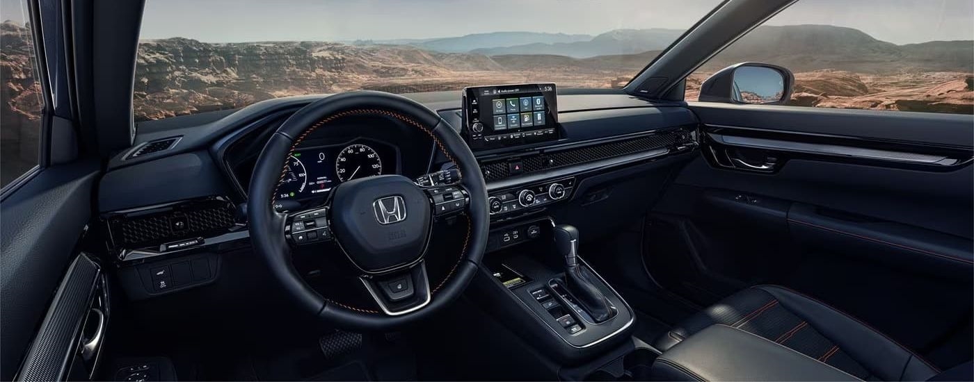 The black interior of a 2024 Honda CR-V is shown from the driver's seat.